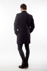 Handsome man in black winter coat, black jeans and boots isolated on white background.