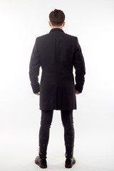 Handsome man in black winter coat, black jeans and boots isolated on white background.