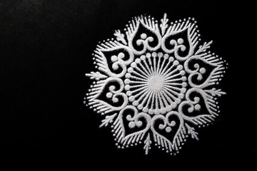 top view of beautiful white rangoli design on black background with copy space in the left. dipawali concept
