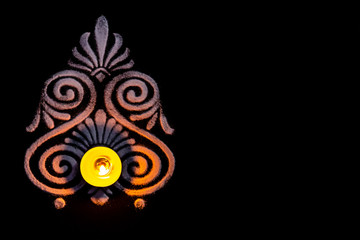 top view of glowing tea lamp and beautiful white color rangoli on balck background with copy space. diwali concept
