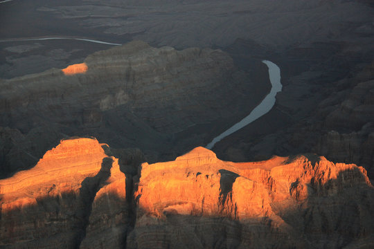 First Sun Rays of the Day illuminating a Rock Formation while the Colorado River is still in the Shadow - Grand Canyon National Park, AZ, USA