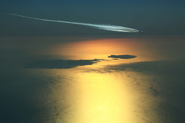 Engine exhaust contrails forming behind an Super Jumbo while overflying the Maltese archipelago during a beautiful sunset