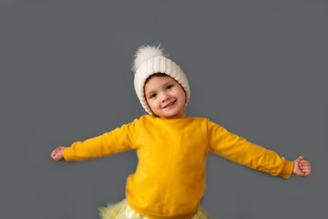 Funny caucasian child in yellow and hat on gray