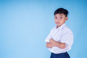 An Asian Muslim school boy wearing white shirt, blue pants school uniform and backpack over blue background. Back to school concept. Isolated. Landscape orientation. 