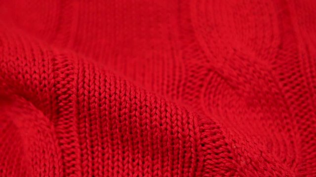 Close-up of red knitted fabric texture. Knitted texture of cozy and soft cotton plaid, textiles, clothing.
