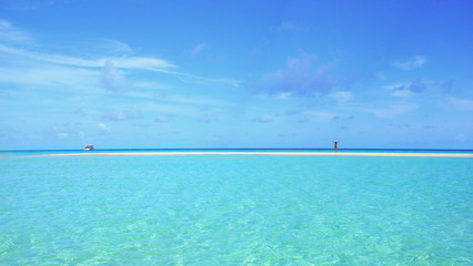 Fototapeta na wymiar Girl standing on a sandbank surrounded by crystal clear turquoise waters at Rasdhoo atoll, Maldives