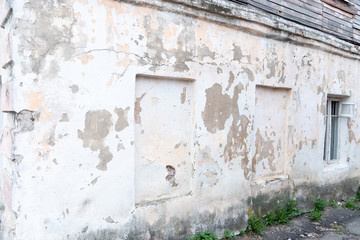 Fragment of the wall of the old building facade, peeling white paint, under which a cement texture.