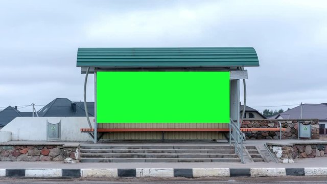 large modern scoreboard with green chroma-key screen under special grey roof against various houses zoom in