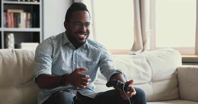 Happy african guy holding joystick playing winning video game