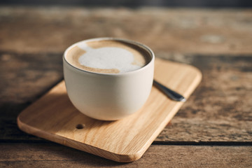 Hot coffee cup and coffee beans on wooden table..