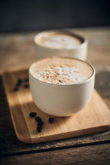 Hot coffee cup and coffee beans on wooden table..