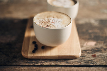 Hot coffee cup and coffee beans on wooden table..