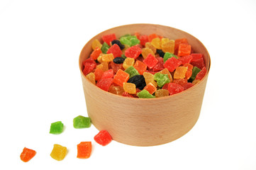 Assorted candied fruits in a wooden pot on a white background