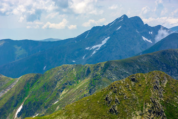 Obraz premium peaks of mountain ridge above the clouds. gorgeous scenery of romanian mountains. fagaras massif in summertime