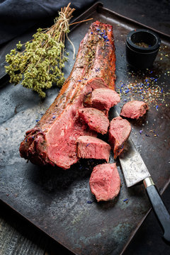 Gegrilltes dry aged Hirsch Filet mit Medaillon Steaks natur mit Kr&auml;uter angeboten als Draufsicht auf einem rustikalen Metall Tablett