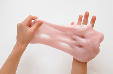 Child hands with pink slime on background.