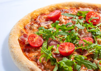 Italian hot pizza with tomato, arugula and pieces of bасon isolated on white background