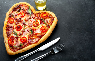  heart-shaped pizza for Valentine's day on a stone background. Valentine's Day gala dinner for two with copy space for your text.