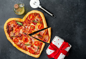 pizza in the form of a heart for Valentine's Day and a gift with a red ribbon on a stone background.  valentine's day dinner concept