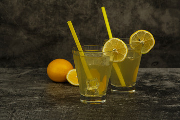 Fresh lemon juice with ice with fresh lemons on a gray background. Lemonade with fresh lemons on a gray background. Fresh juice lemonade.