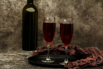 Two glasses of wine with a bottle on a gray background. Wine in glasses on a background of old concrete.