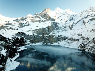 Fototapeta na wymiar Kandersteg BE, Schweiz: Der gefrorene Oeschinensee reflektiert die Berge des Berner Oberlands, die ihn umgeben