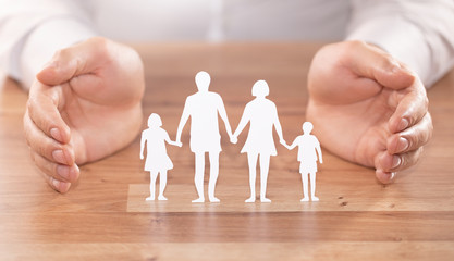 Fototapeta na wymiar Family care concept. Hands with paper silhouette on table.