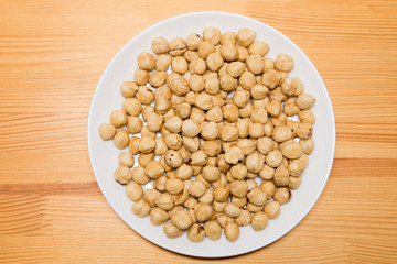 Whole hazelnuts in white plate on the wooden background. Healthy vegetarian snack. Close-up photo. 