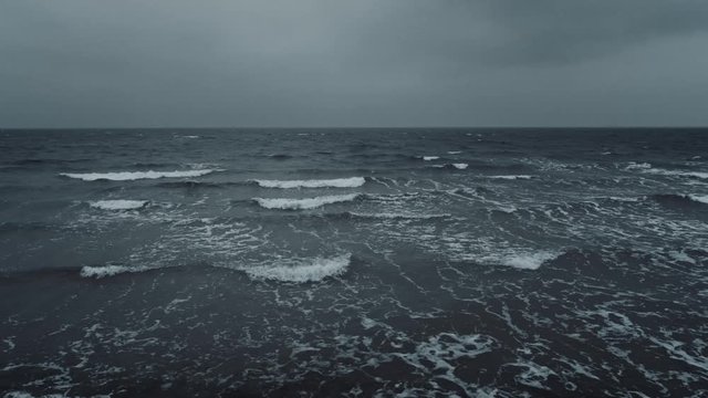 Dramatic slow motion sea or ocean waves with overcast sky at sunset. 