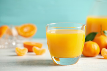 Glass of fresh tangerine juice and fruits on white wooden table