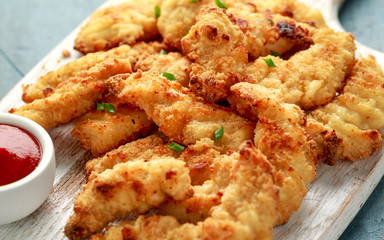 Buttermilk chicken nuggets with ketchup on wooden board