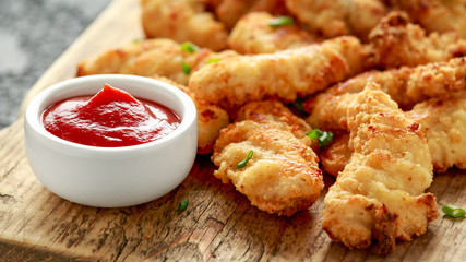 Buttermilk chicken nuggets with ketchup on wooden board