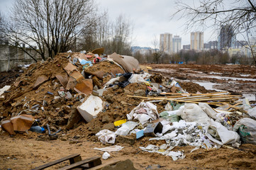 The concept of trash environmental disaster. Photo of a landfill on a street in a city on a cloudy day.