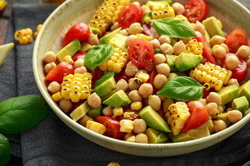 Avocado chickpea salad with grilled sweet corn, tomato and basil. Healthy vegan food