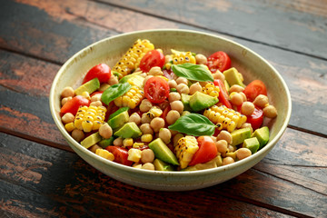 Avocado chickpea salad with grilled sweet corn, tomato and basil. Healthy vegan food