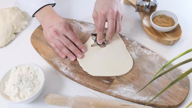 Man Cutting a Star Shaped Cookie out of Cookie Dough on white table with wooden board. Close up.