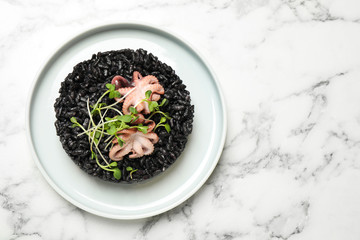 Delicious black risotto with seafood on white marble table, top view. Space for text