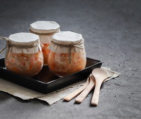 Sauerkraut with carrots and cumin in a jar on a linen napkin with a wooden spoon in a rustic style on a dark background