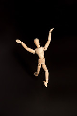 a wooden figure of a man gelstat runs in horror on a black background