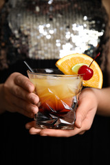 Woman with glass of Tequila Sunrise, closeup. Delicious alcoholic cocktail