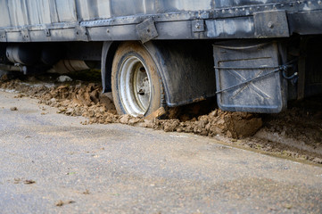 Photo of a heavy truck stuck in mud and skidding in place on a cloudy day.