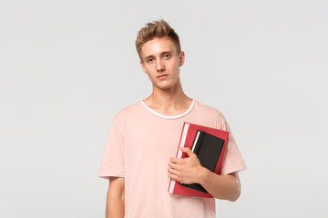 Pretty young man in a pink t-shirt with books and files.
