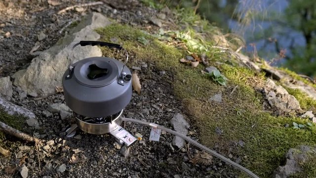 kettle is heated on portable gas burner outdoors. concept of Tea party on camping trip.