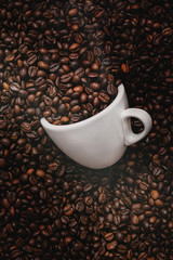 white coffee cup lies in roasted coffee beans of the highest standard