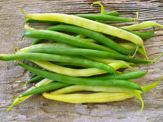 Green and yellow bean pods of asparagus on old rustic wooden table. Freshly harvested raw beans on wooden background. Closeup, selective focus.