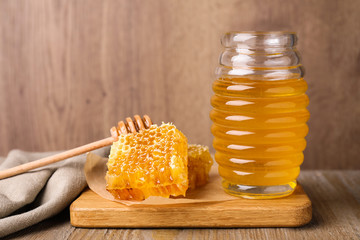 Jar of tasty aromatic honey and combs on wooden table