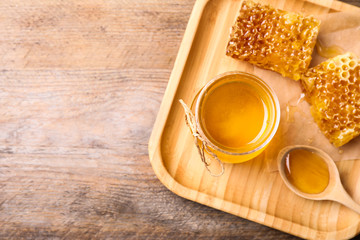 Tasty aromatic honey on wooden table, flat lay. Space for text