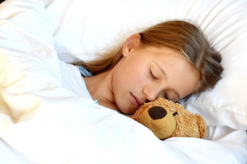 Obraz na płótnie Canvas A teenage girl sleeps with a Teddy bear. Favorite toy in bed. Sladky healthy sleep of a child.