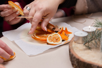 Women's hand making decorations from dried oranges, stars from tangerine and cinnamon. Girls party or meeting
