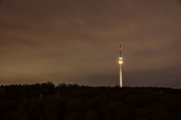 Fototapeta na wymiar Germany, Famous illuminated tv tower building in endless forest nature landscape of city stuttgart by night